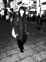 A lone traveler standing on a bustling Tokyo street at night, lights glowing around them, symbolizing the outsider's journey.