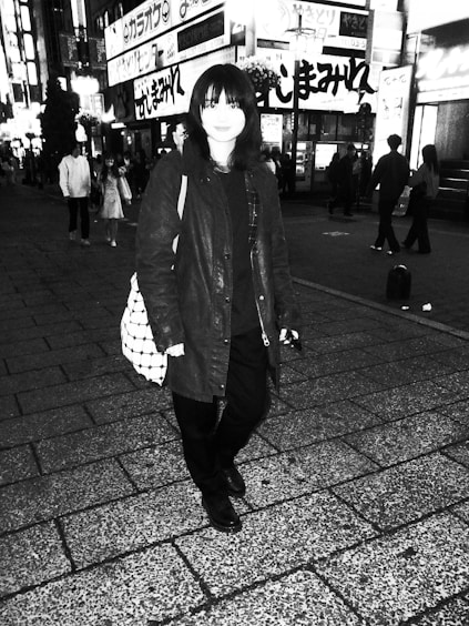 A lone traveler standing on a bustling Tokyo street at night, lights glowing around them, symbolizing the outsider's journey.