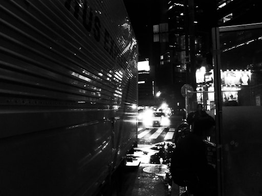 Tow truck rescuing a car on a roadside at night with city lights in the background