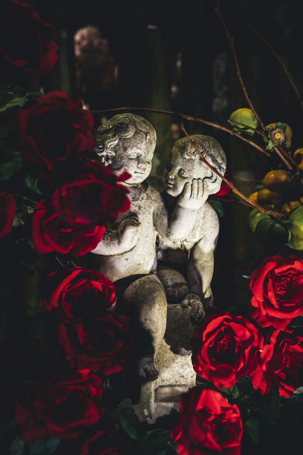 a statue of two cherubs surrounded by red roses