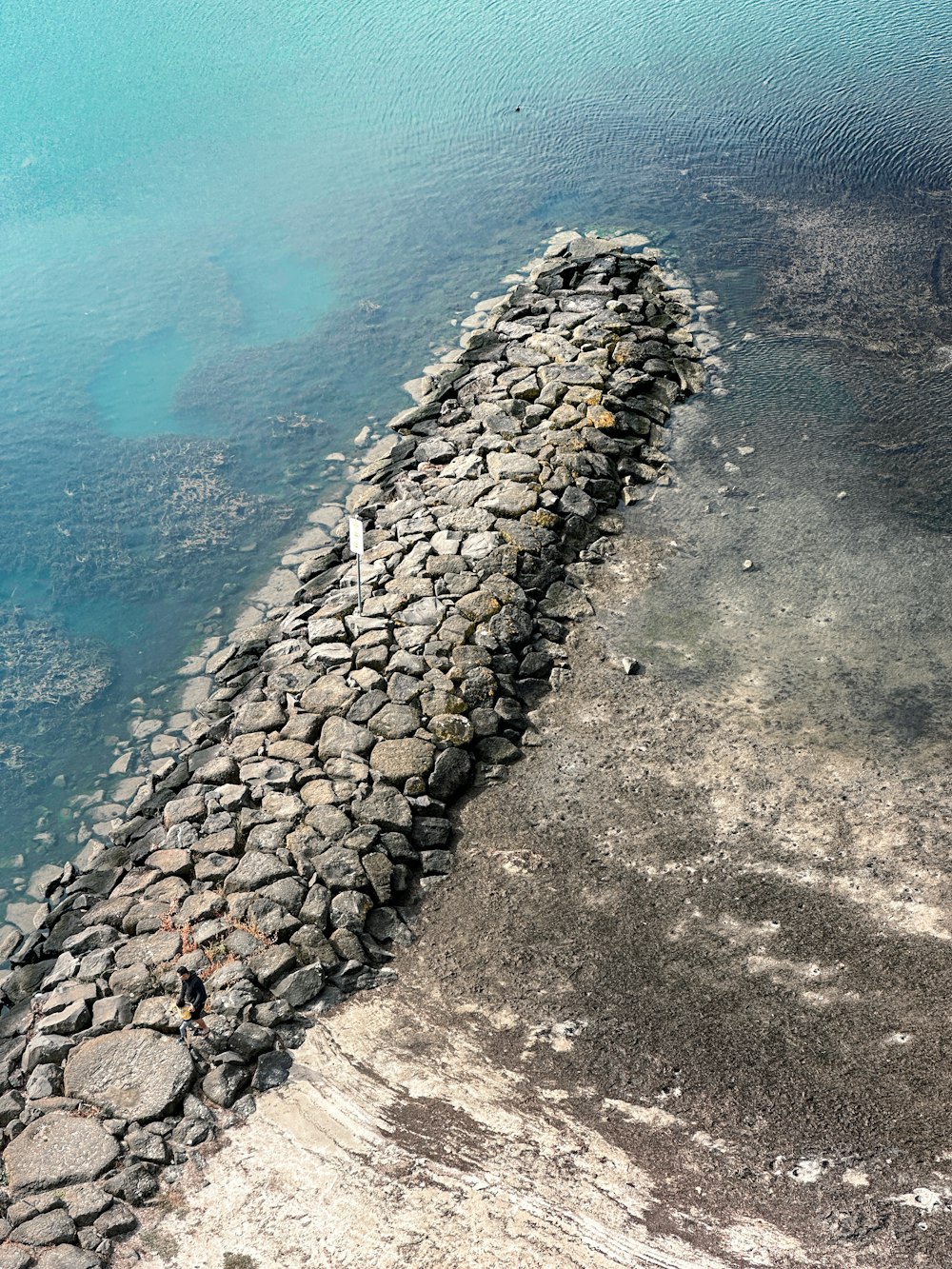 a stone wall next to a body of water