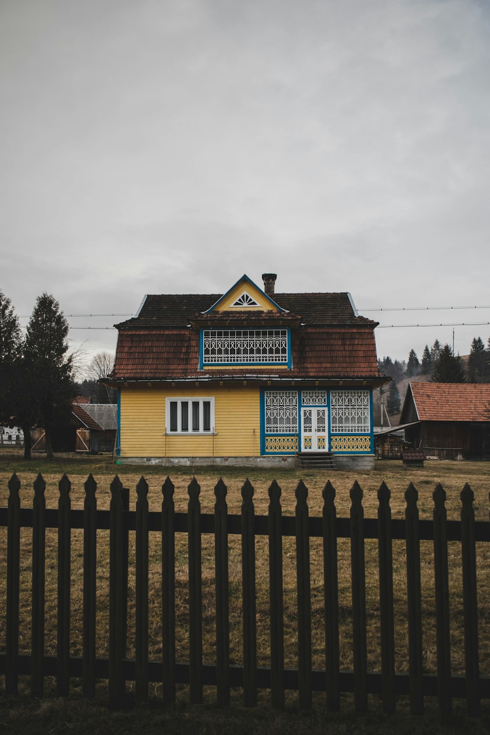 a yellow and blue house with a black fence