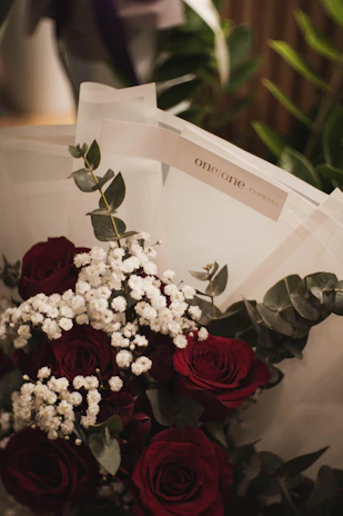A romantic arrangement of red roses with baby's breath, wrapped in soft pink paper.