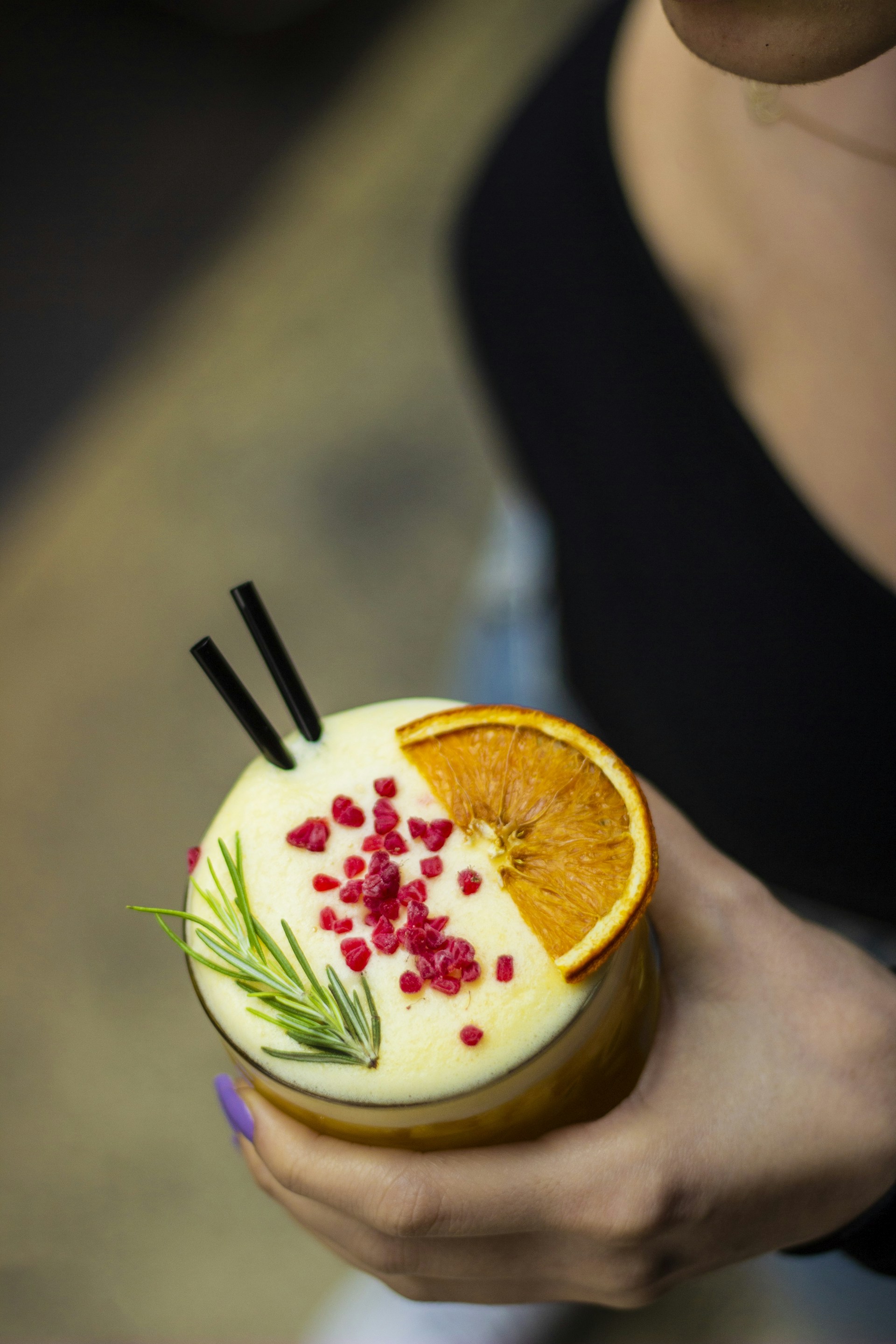 a person holding a drink with orange slices and garnishes