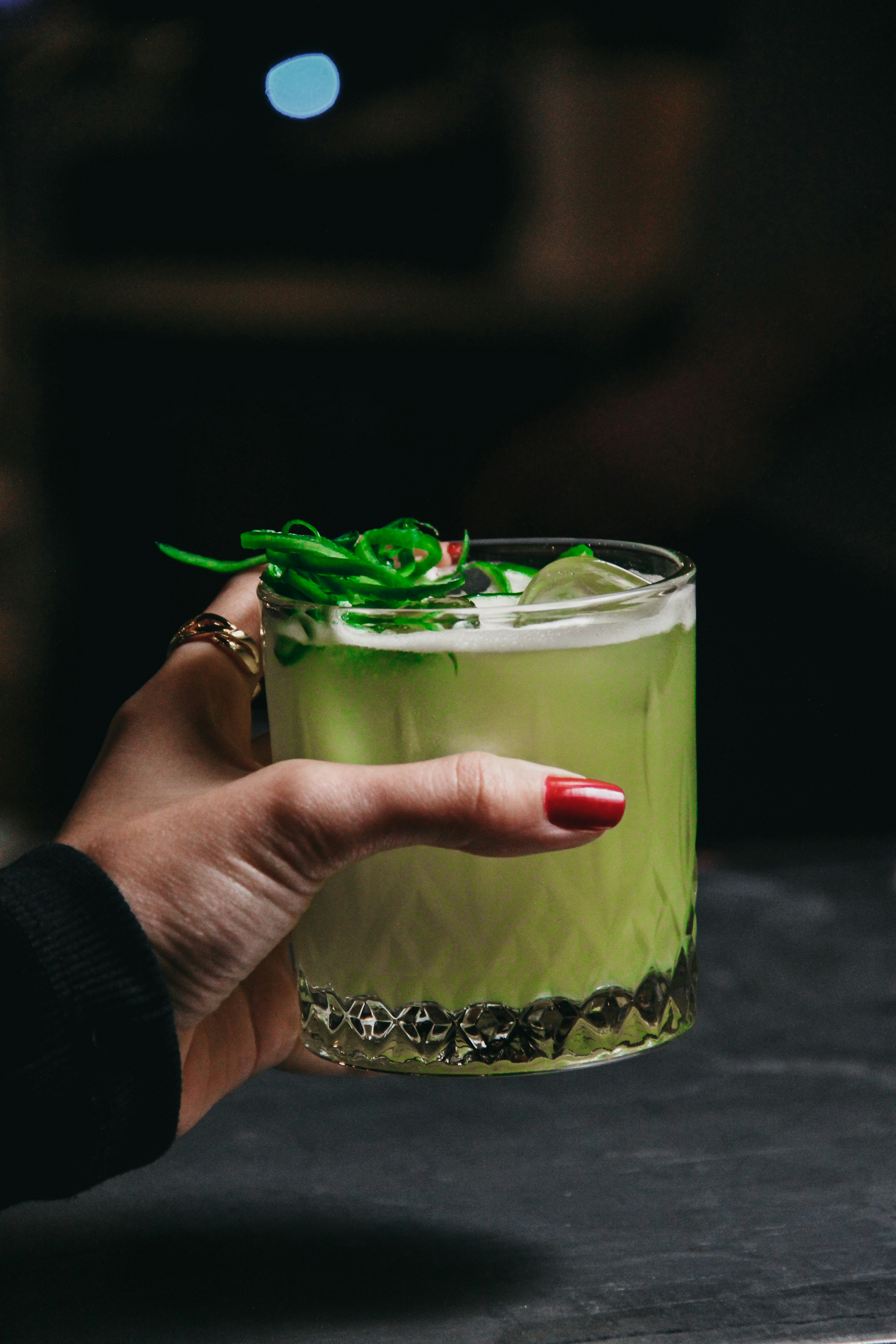 a person holding a green drink in their hand