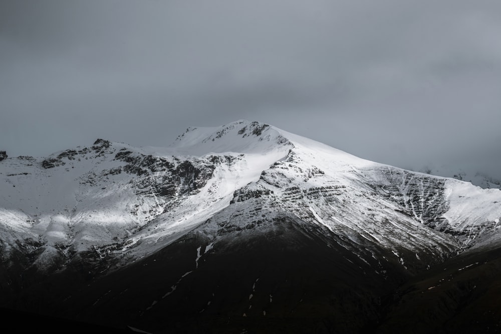 a mountain covered in snow under a cloudy sky