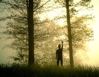 The silhouette of a girl standing quietly, listening to the wind as it moves through the trees.
