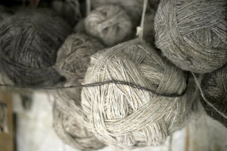 Several loosely wound balls of yarn in various shades of gray and beige, showcasing a textured and fibrous appearance.