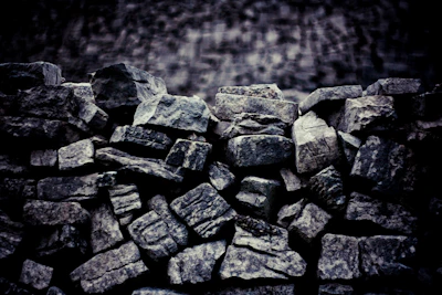 Workers inspecting stone quality amid piles of freshly crushed material.