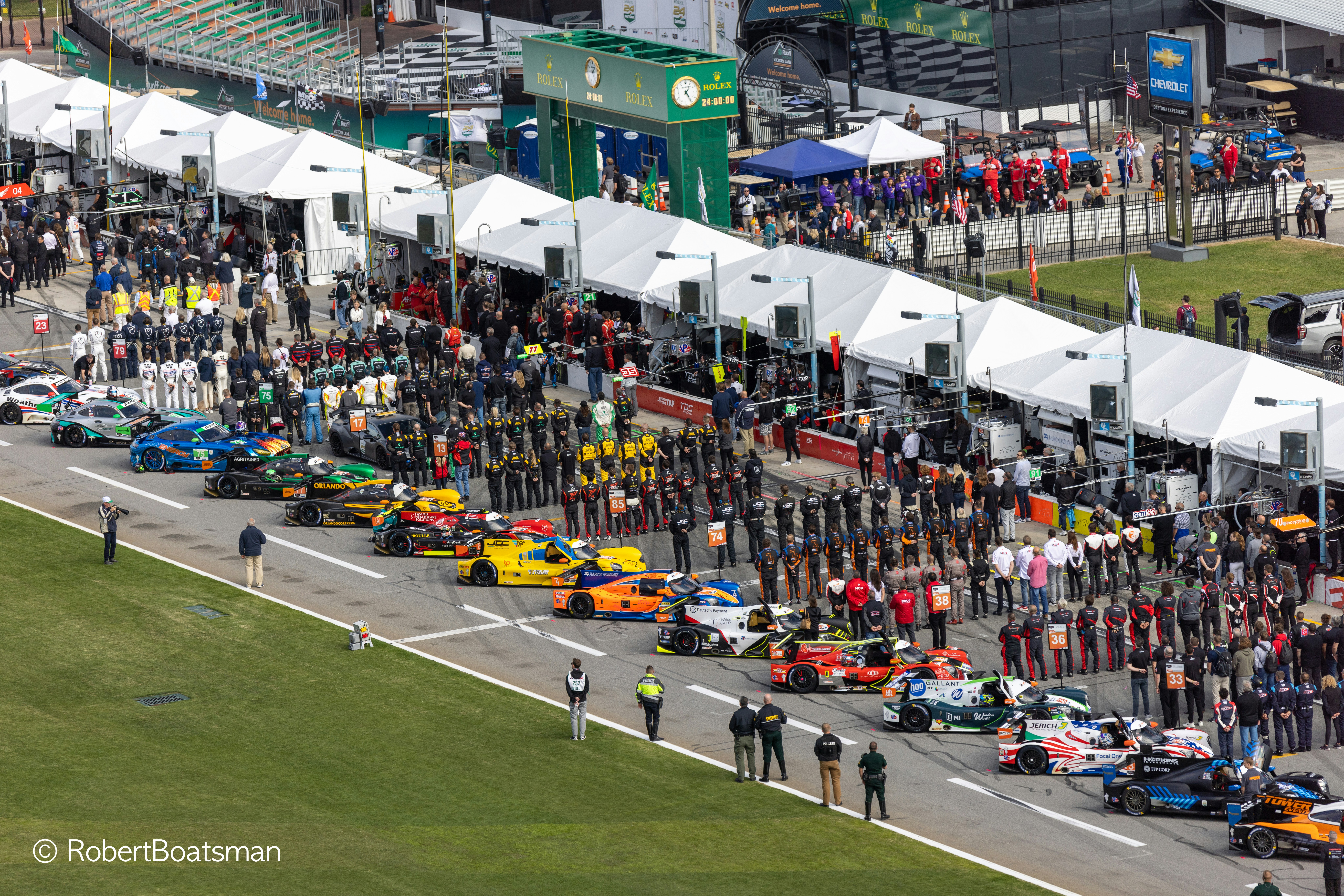 A group of people standing around a race track photo – Free Car Image ...