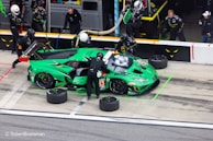 Team 988's car parked in the service area, surrounded by crew tuning and prepping.