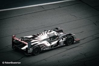 A sleek, high-performance racing car is captured on a motor racing track. The car features an aerodynamic design with prominent branding and markings, including the number 88. The image is taken from a high angle, showcasing the car's intricate details and emphasizing its speed and agility.