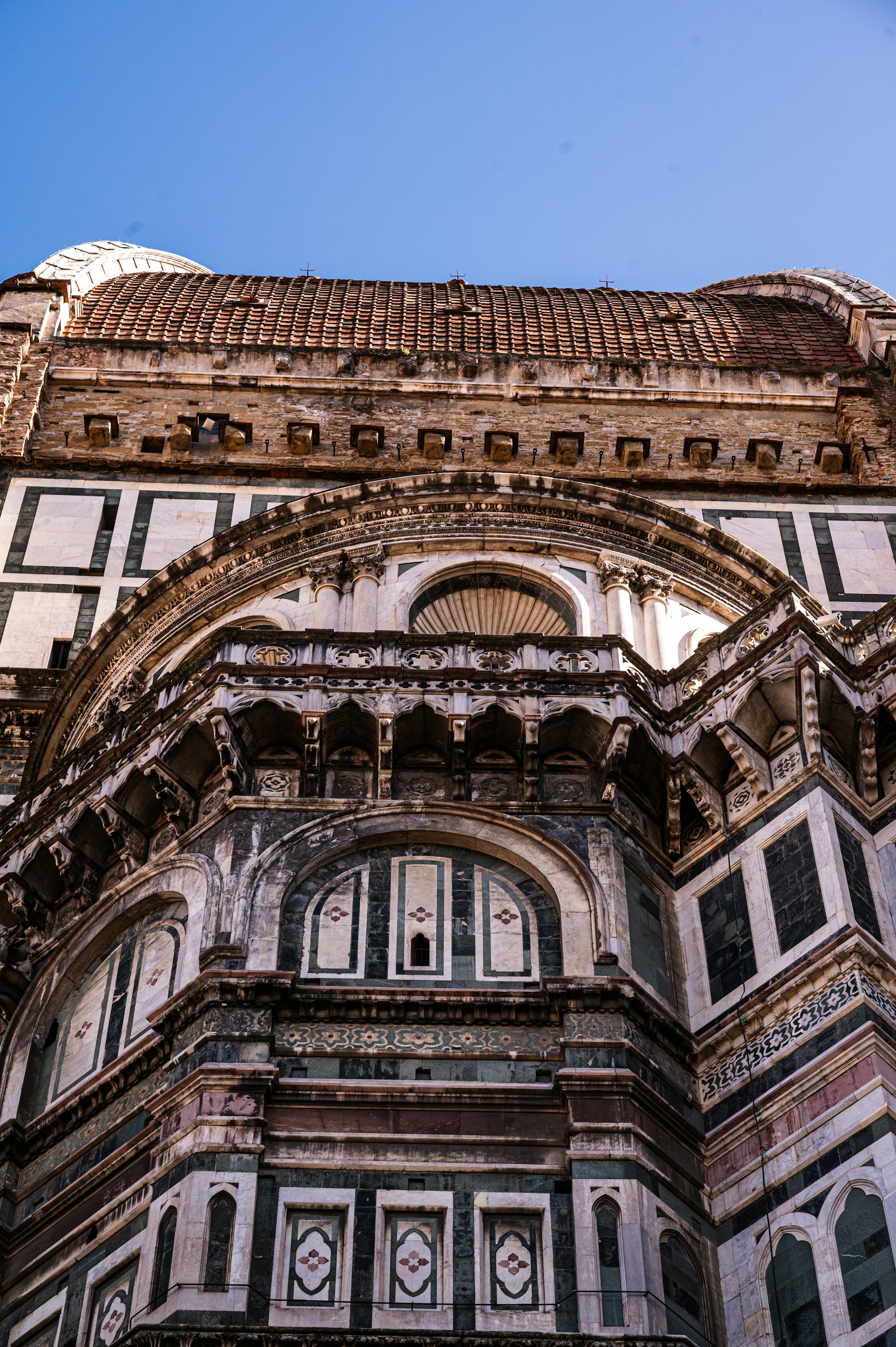 A beautifully crafted custom home exterior showcasing intricate stonework and elegant architectural details under a clear blue sky.