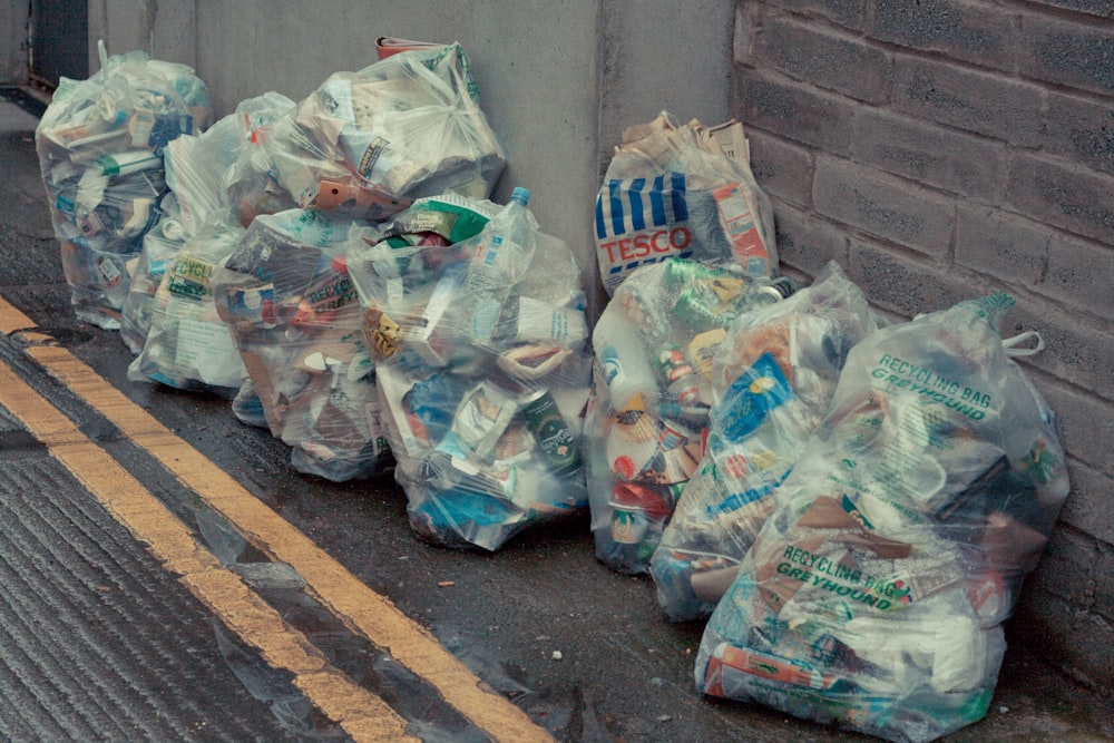 a bunch of bags of garbage sitting on the side of a road