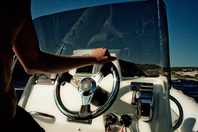 Close-up of a student confidently handling the boat's steering wheel under guidance.