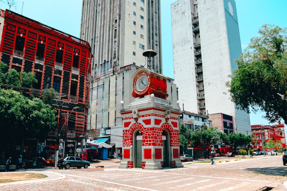 a red and white clock tower in the middle of a city
