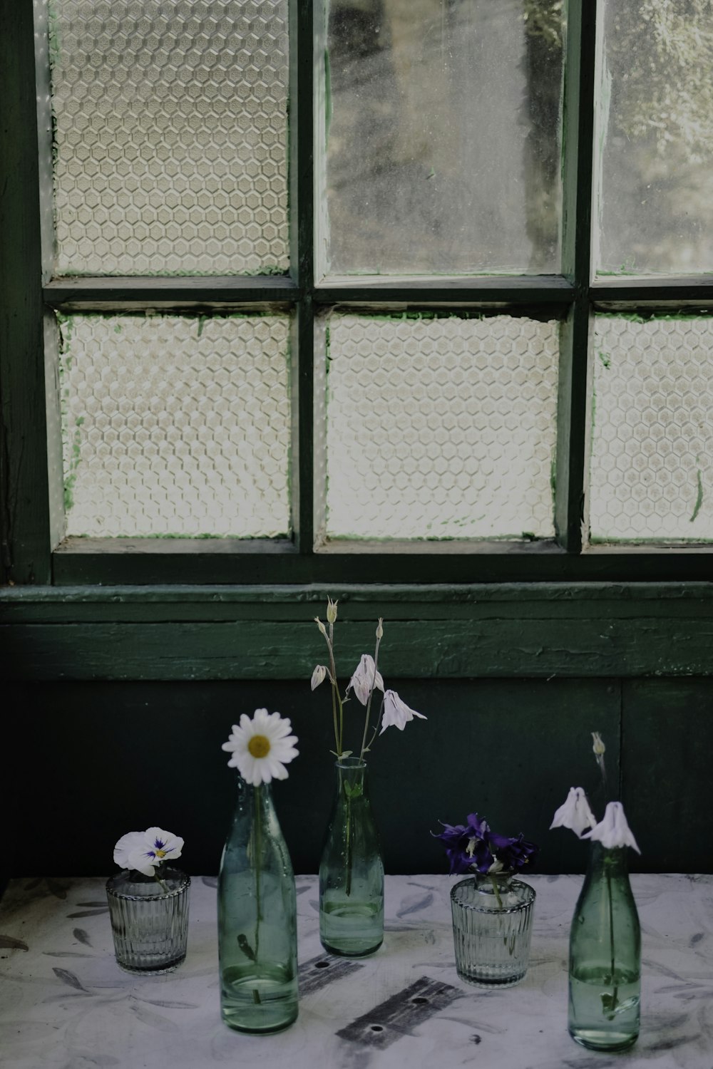 three vases with flowers in them sitting on a table