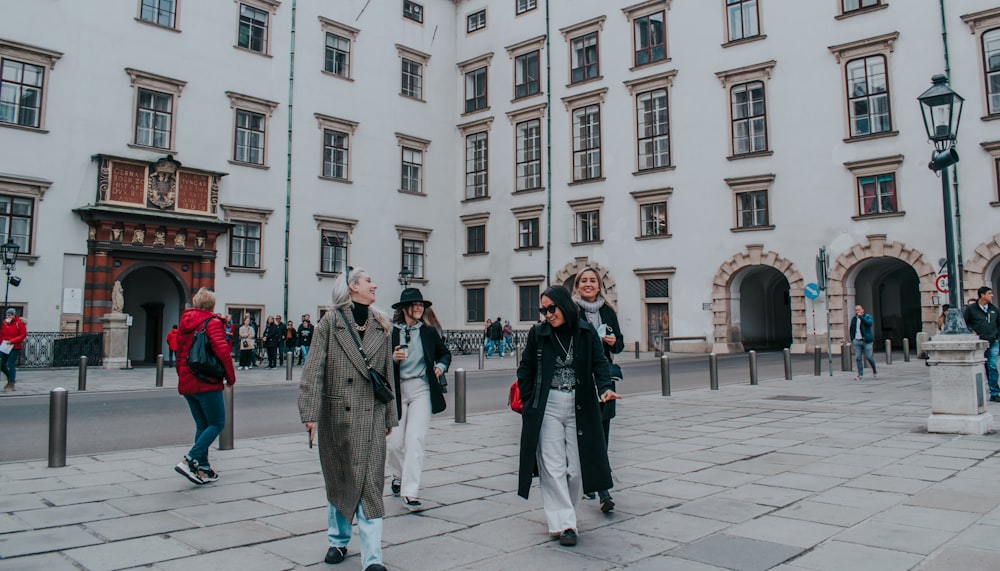 a group of people walking down a street next to tall buildings