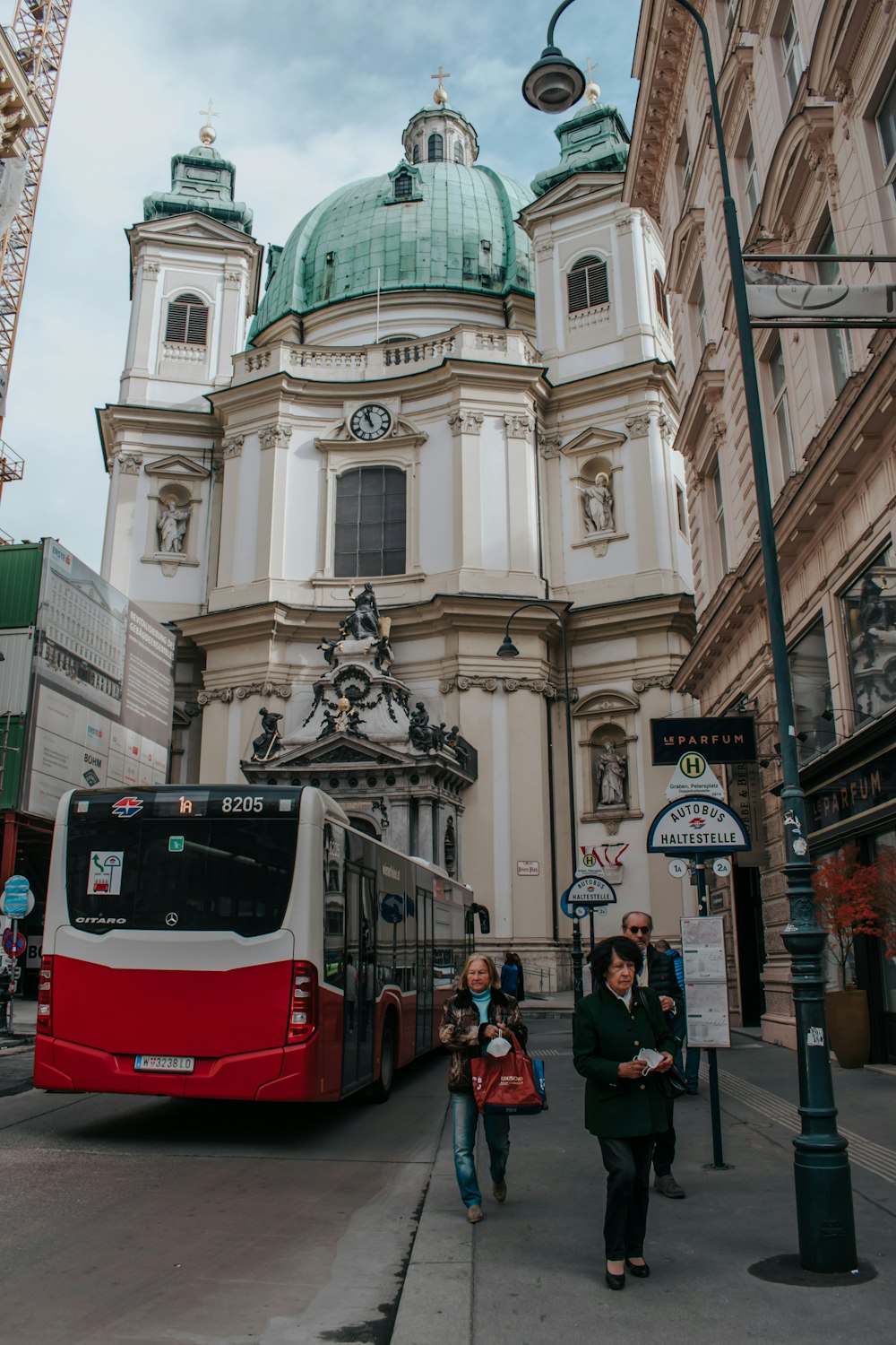 a red and white bus driving past a tall building