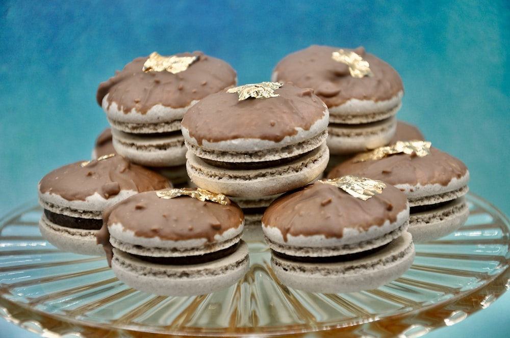 a plate of cookies with chocolate frosting and gold decorations