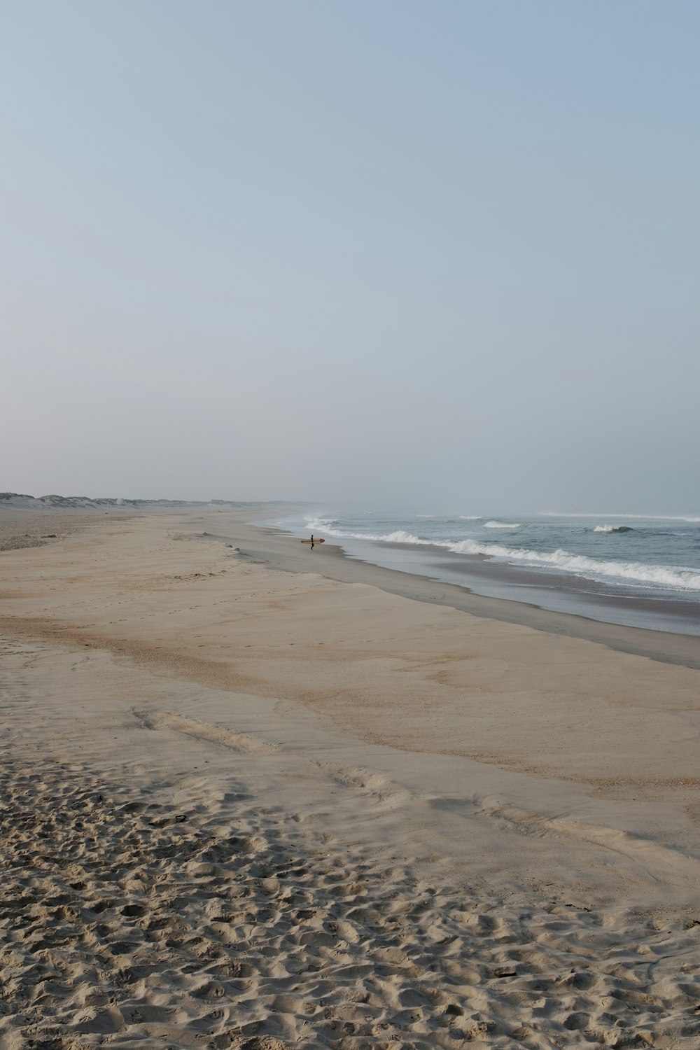 a person walking along a sandy beach next to the ocean