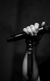 Close-up of hands holding a microphone with graffiti art in the background.