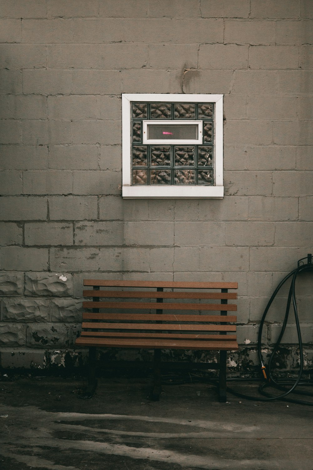 a wooden bench sitting in front of a brick wall