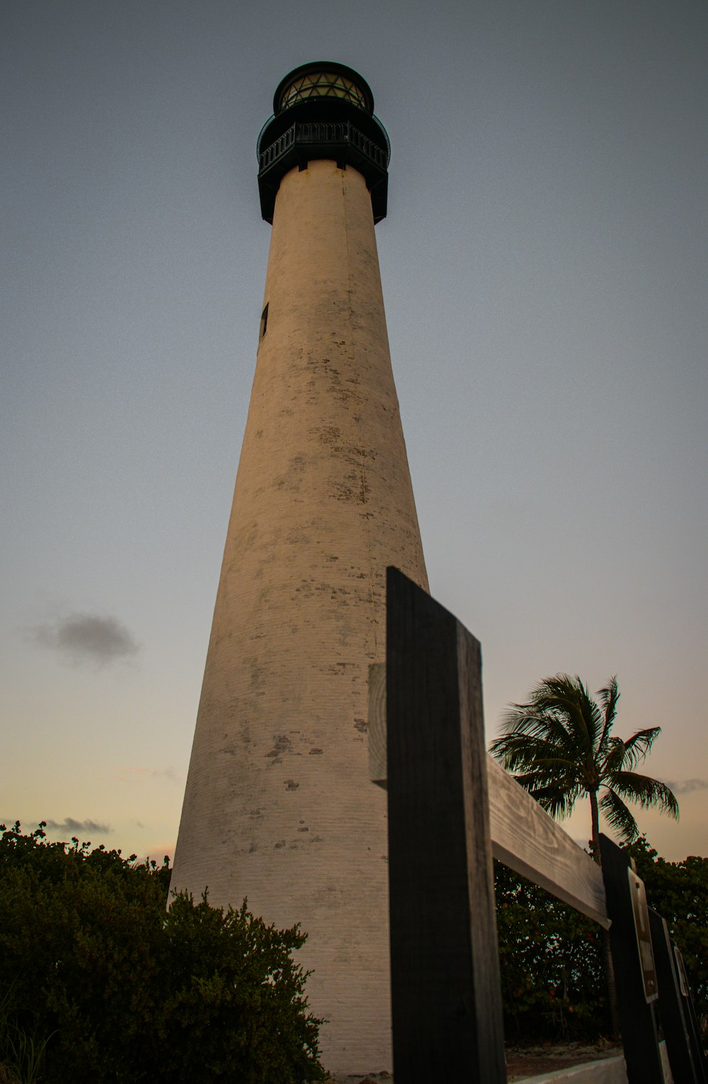 a tall light house sitting next to a lush green forest