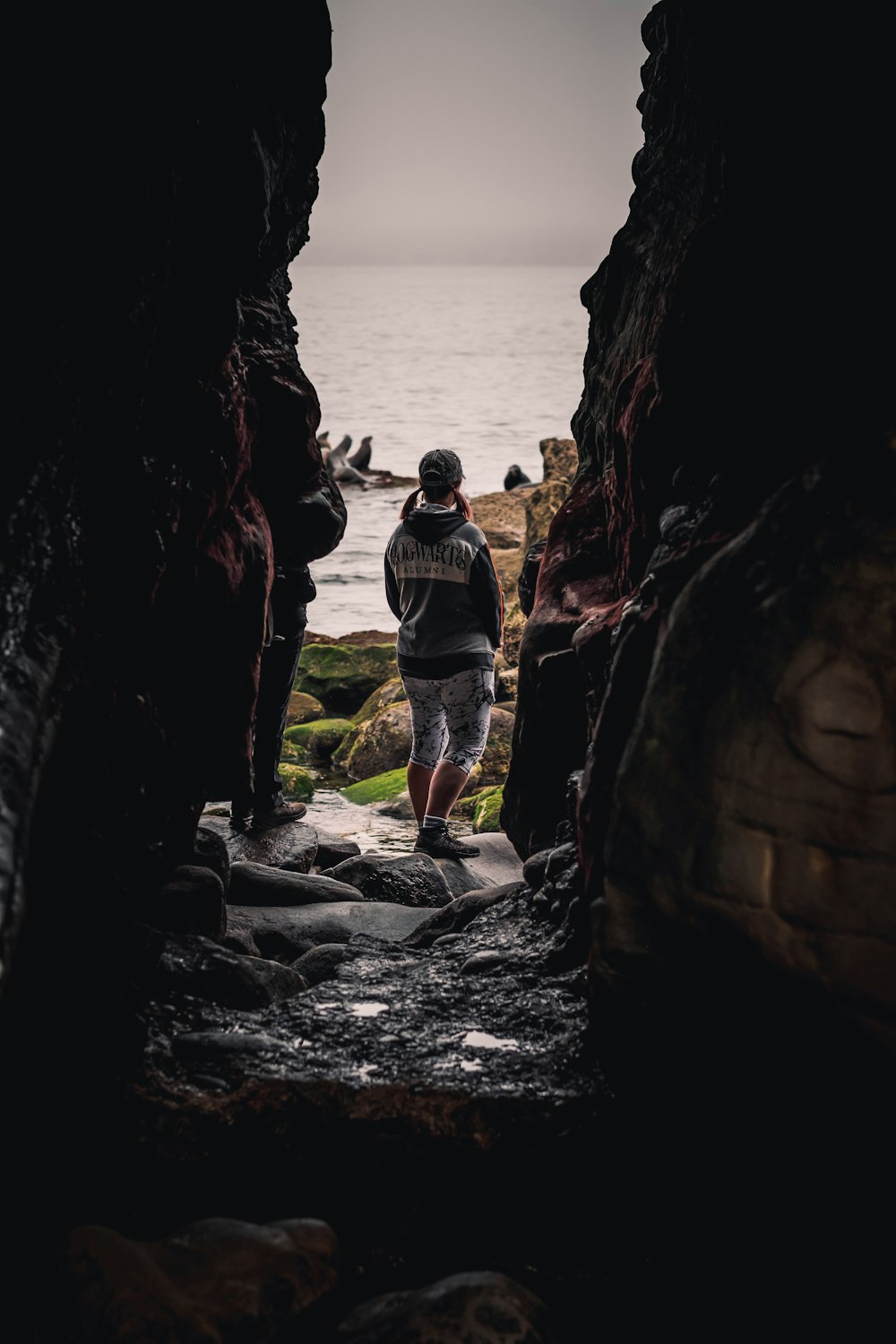 a man standing in a cave looking out at the ocean