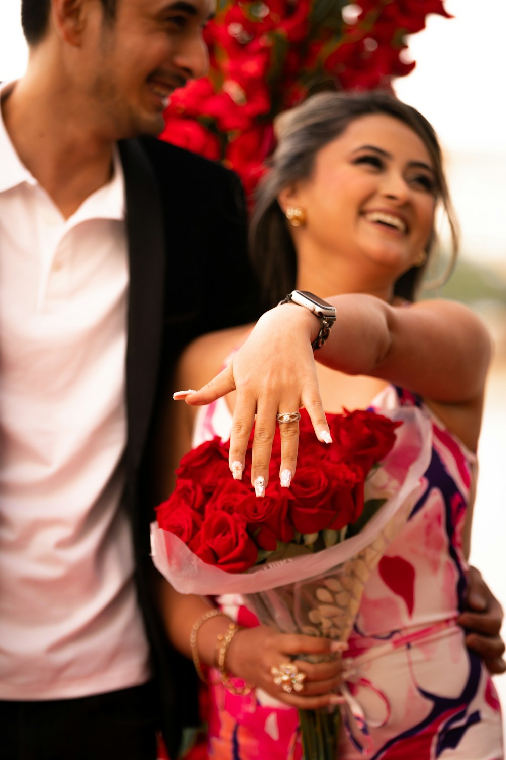 a man holding a bouquet of red roses next to a woman