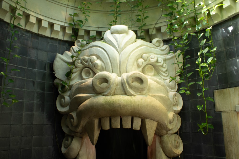 a statue of a dragon head with a plant growing out of it's mouth