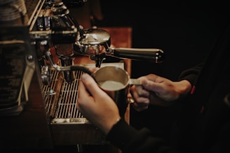 Hands holding a sleek kikkoespresso machine in a cozy kitchen setting