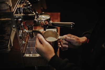 Hands holding a sleek kikkoespresso machine in a cozy kitchen setting
