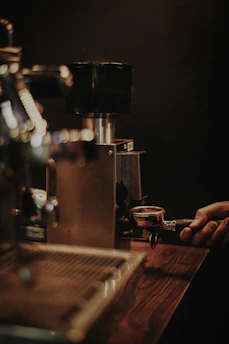 Close-up of a barista adjusting coffee grinder settings during a private lesson.