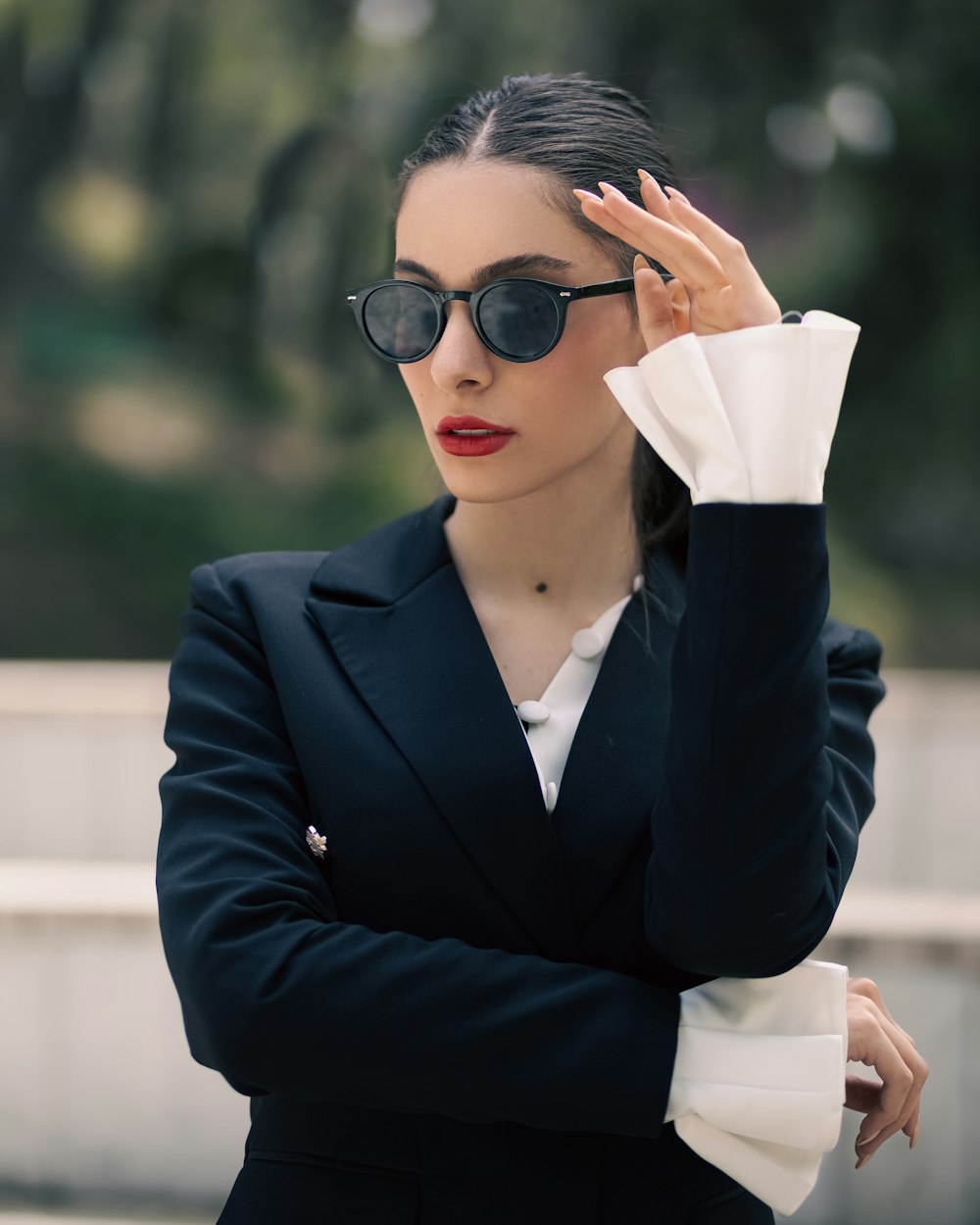 a woman in a black suit and sunglasses