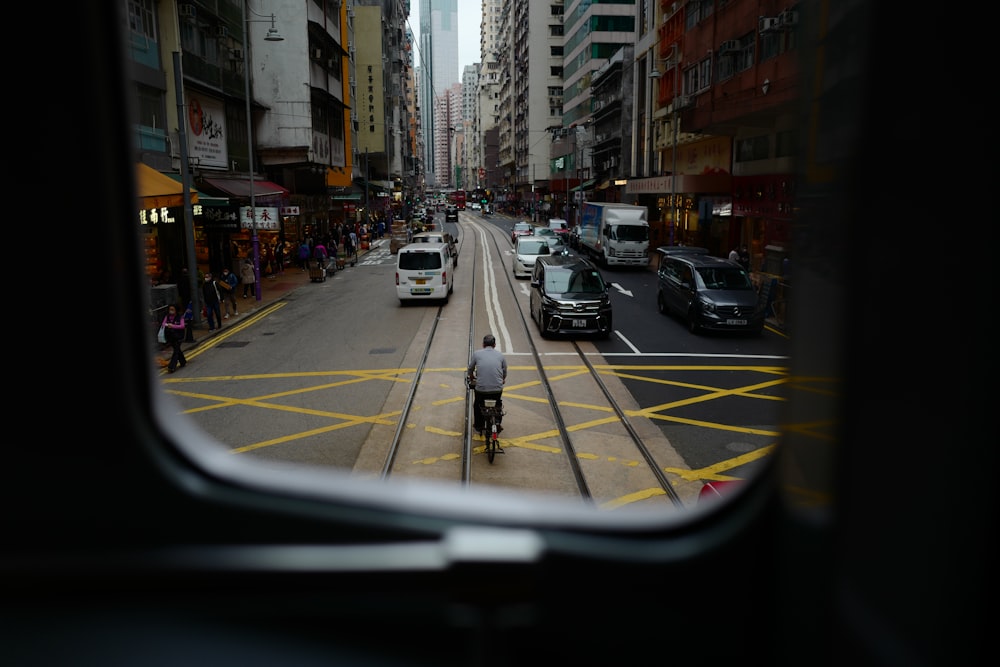 a man riding a bike down a street next to tall buildings