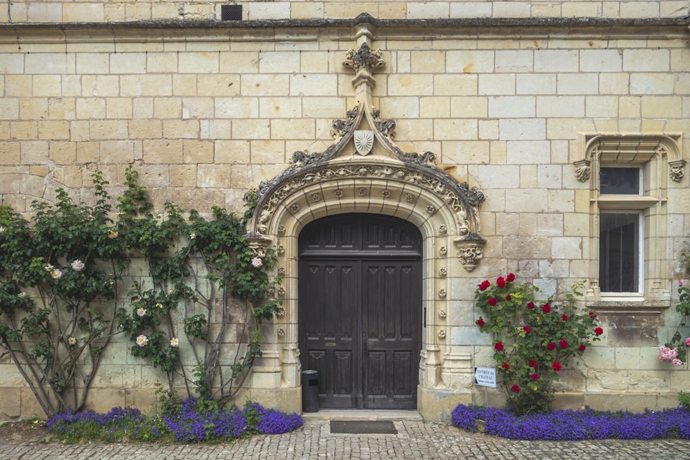a building with a black door surrounded by flowers