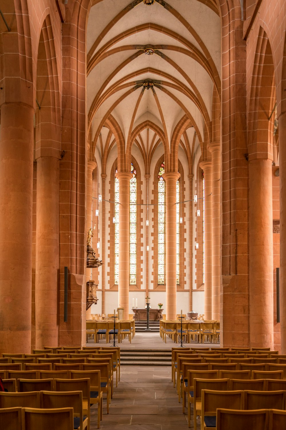木製の会衆席とステンドグラスの窓が並ぶ教会
