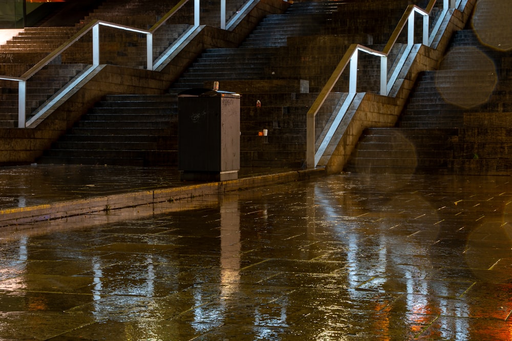 a flooded street with stairs and a trash can
