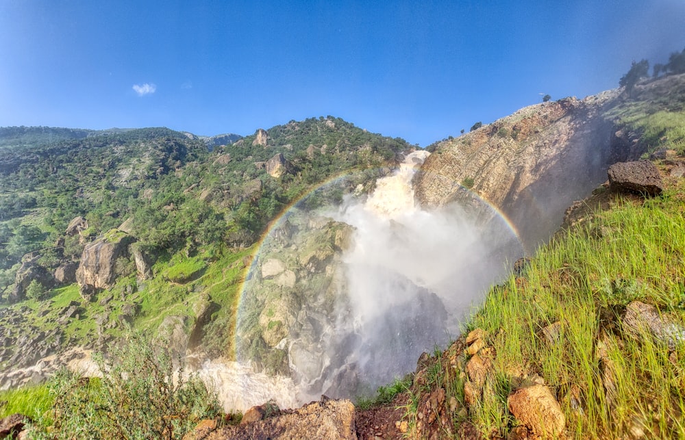 a rainbow in the sky over a waterfall