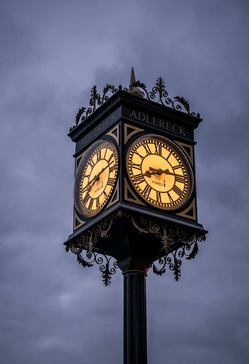 a clock on a pole with a cloudy sky in the background