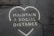 A cracked pavement features a heart-shaped outline with the words 'Maintain a Social Distance' written inside it, conveying a message of social distancing. The cracks in the pavement intersect the text, possibly signifying challenges or wear over time.