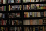 A bookshelf filled with a wide variety of books. The shelf has numerous colorful book spines, including titles in different genres such as mystery, thriller, and historical fiction. The books are neatly organized and arranged in rows, covering the entire available space on the shelf. Notable titles include 'Sea of Flames' and 'Money in the Morgue'.