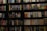 A bookshelf filled with a wide variety of books. The shelf has numerous colorful book spines, including titles in different genres such as mystery, thriller, and historical fiction. The books are neatly organized and arranged in rows, covering the entire available space on the shelf. Notable titles include 'Sea of Flames' and 'Money in the Morgue'.