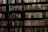 A bookshelf filled with a wide variety of books. The shelf has numerous colorful book spines, including titles in different genres such as mystery, thriller, and historical fiction. The books are neatly organized and arranged in rows, covering the entire available space on the shelf. Notable titles include 'Sea of Flames' and 'Money in the Morgue'.