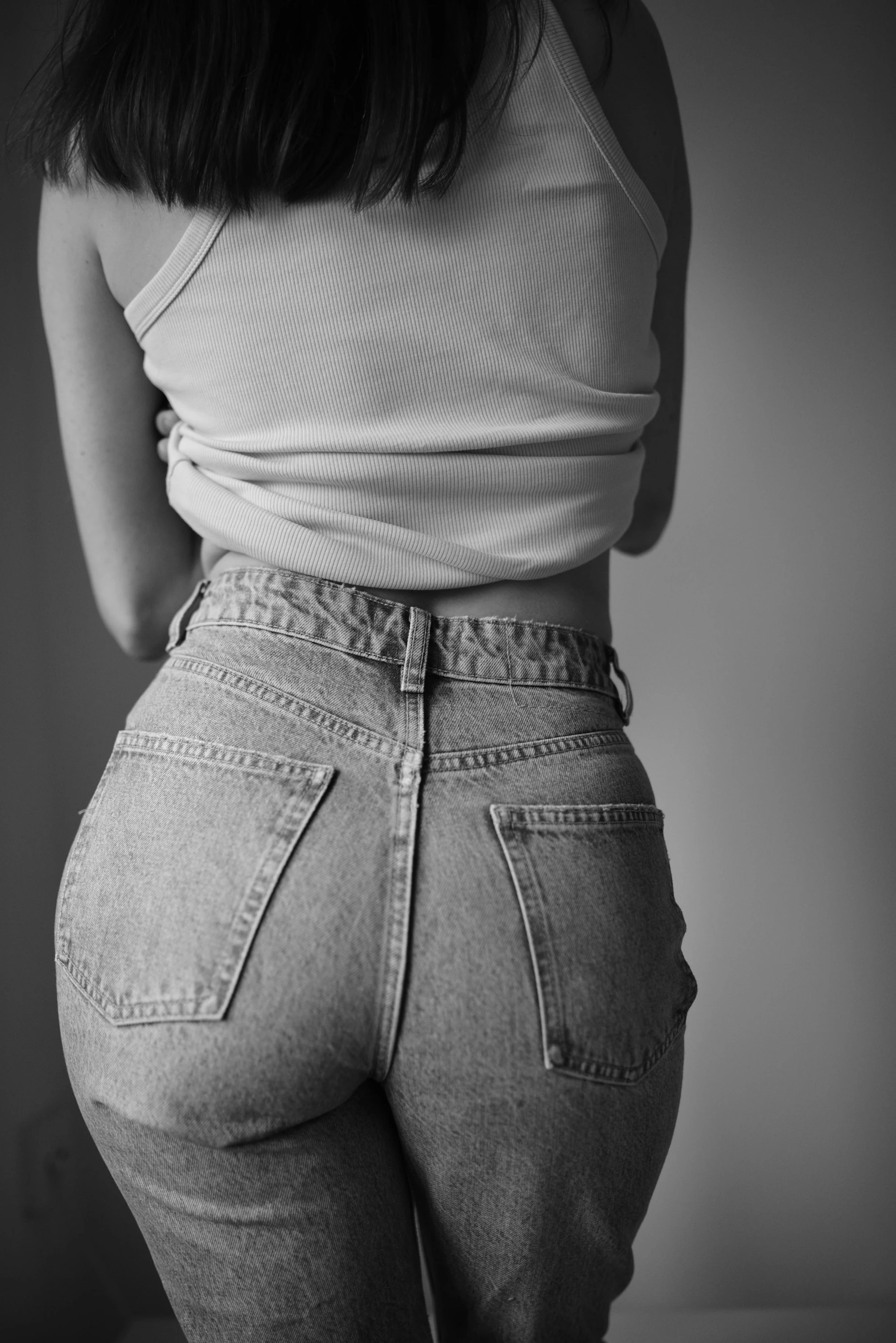 a woman in high waist jeans and a tank top