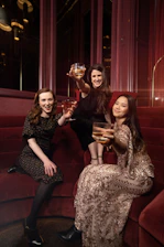 Elegant gathering of women sharing laughter and cocktails in a stylish, modern lounge.