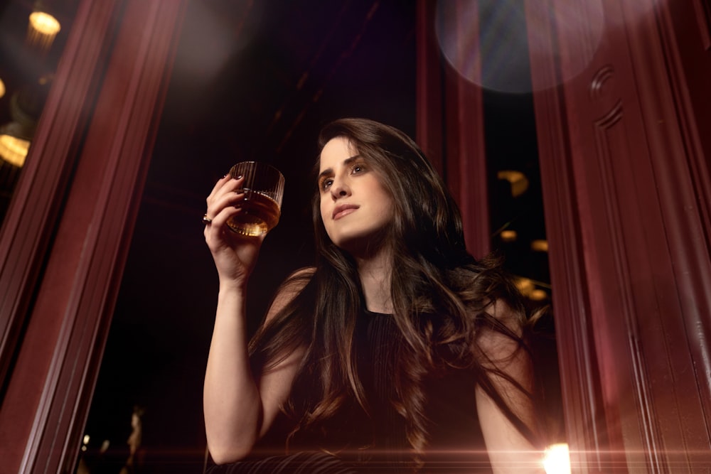 a woman in a black dress holding a glass of wine