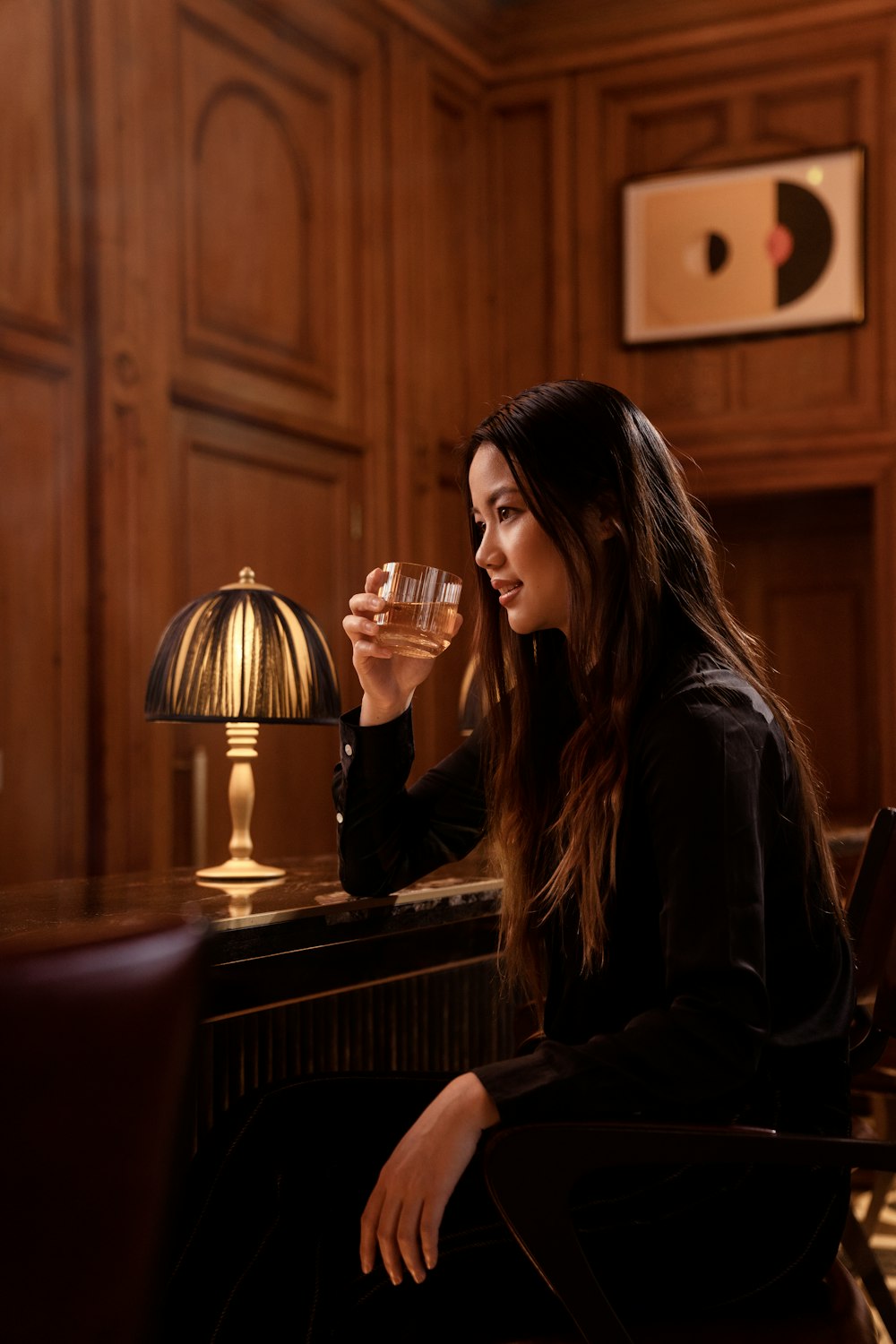 a woman sitting at a bar drinking a glass of wine