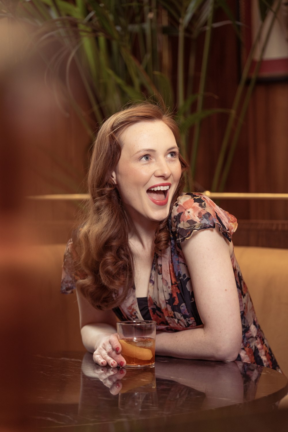 a woman sitting at a table with a drink